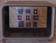 In einem alten Radiogehäuse sind 9 Glascheiben mit dünnen Drähten montiert. Dahinter ist je eine LED. Die 9 Lichter werden zufällig angesteuert.